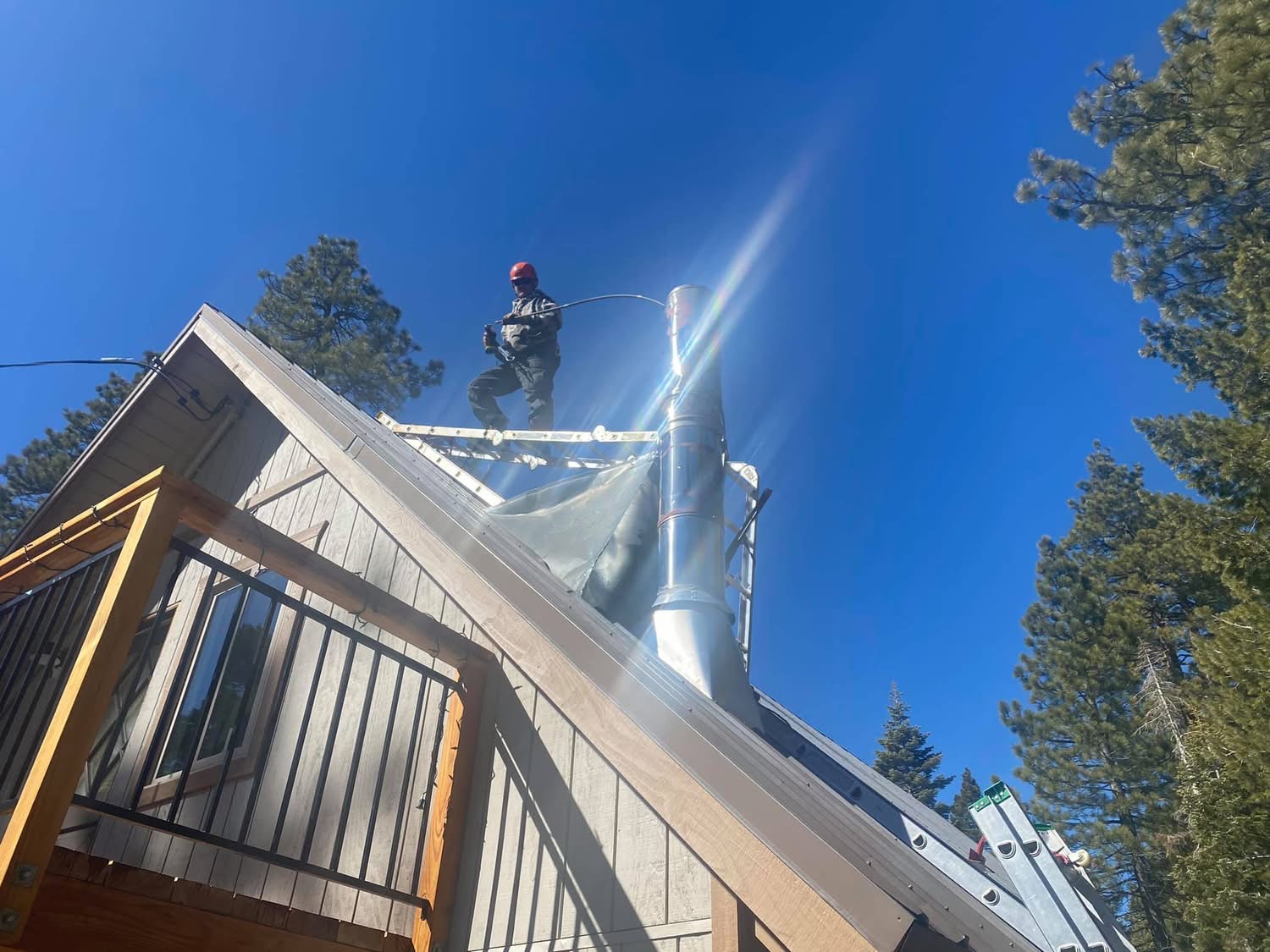 Billy cleaning a metal chimney from the roof.