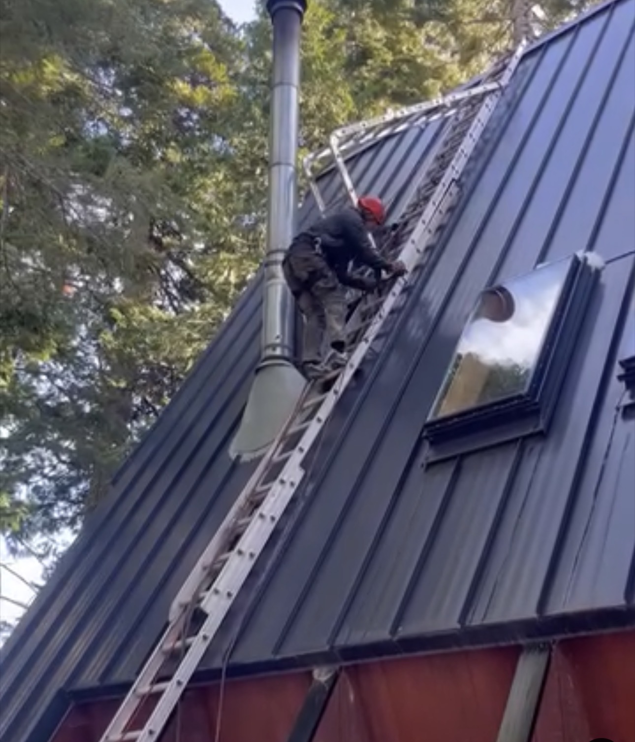 Billy working on a steep metal roof with a ladder